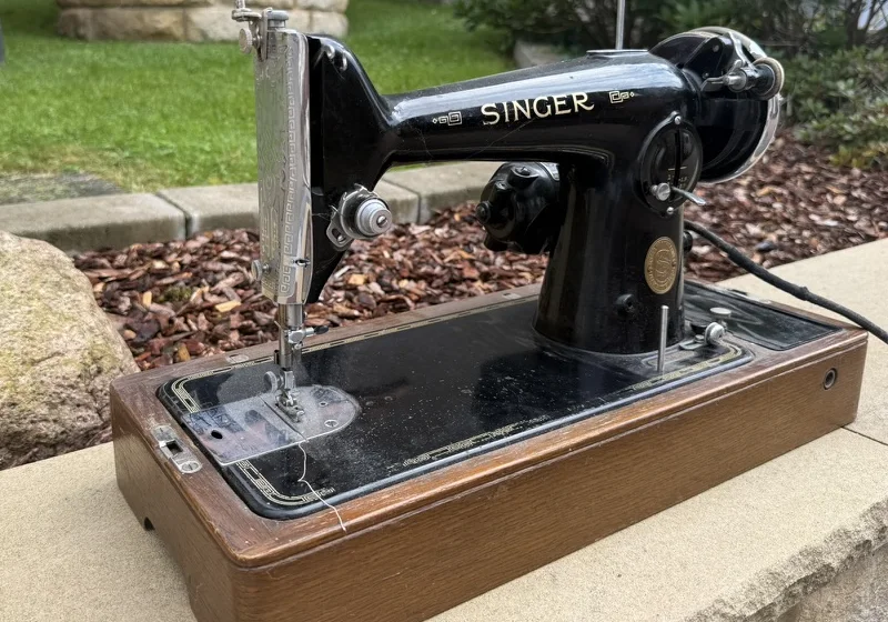 A vintage black Singer sewing machine with gold decals on a wooden base.